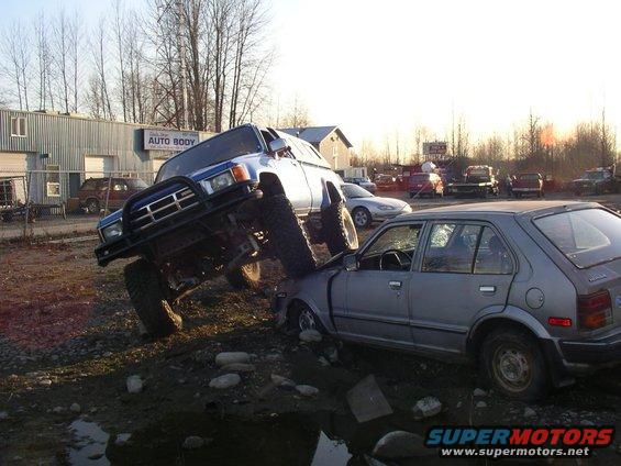 Blue Toyota 4Runner crushing silver Honda Civic in junkyard