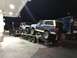 1991 Ford Bronco - A blue and tan 1991 Ford Bronco is transported on a trailer alongside other vehicles.
