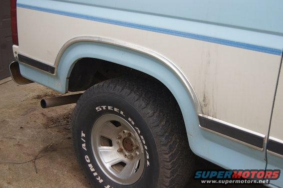 Rear quarter panel and tire of a light blue and white pickup truck. "STEEL KING A/T" is visible on the tire