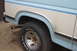 1986 Ford Bronco - Close-up of the rear wheel well and side panel of an older pickup truck.
