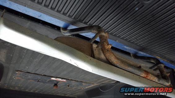 running board bracket and some rusty pipes underneath a vehicle