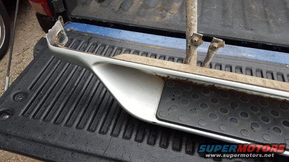 Running board assembly with metal brackets and rubber grip pad, resting in a truck bed