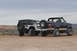 1991 Ford Bronco - Two modified SUVs, a 1991 Ford Bronco and a Jeep Wrangler, are parked side-by-side on a dirt track.