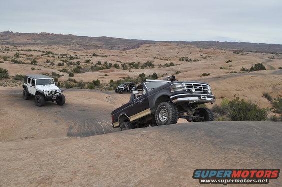 Black Ford Bronco and white Jeep off-roading on rocky desert terrain
