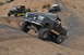 1991 Ford Bronco - A lifted Ford Bronco navigates a steep, rocky trail with other off-road vehicles in the background.