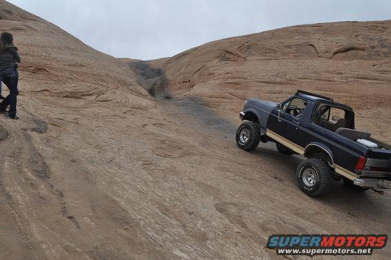 1991 Ford Bronco climbing a steep, rocky incline with a person watching