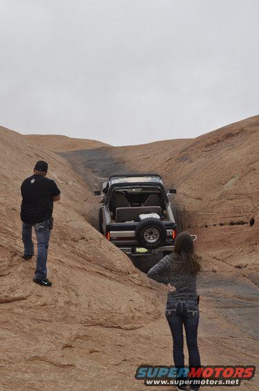 Ford Bronco navigating a rocky off-road trail with two people watching