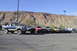 1991 Ford Bronco - A line of off-road vehicles, including a blue and silver Ford Bronco, are parked in a lot with a mountainous backdrop.