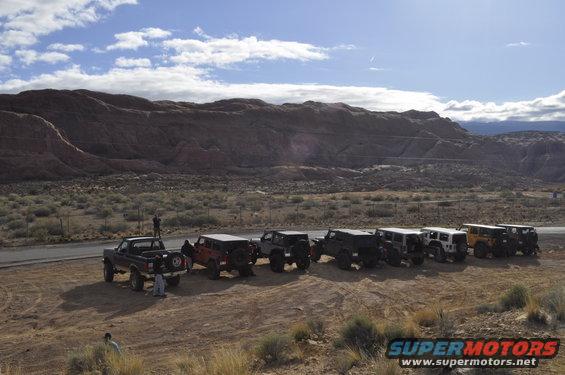 Line of off-road vehicles parked in desert with red rock formations