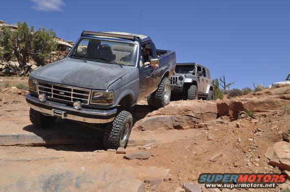 Gray Ford F-Series truck with aftermarket light bar navigating a rocky trail