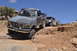 1991 Ford Bronco - A gray Ford F-Series truck leads a convoy of off-road vehicles on a challenging desert trail.