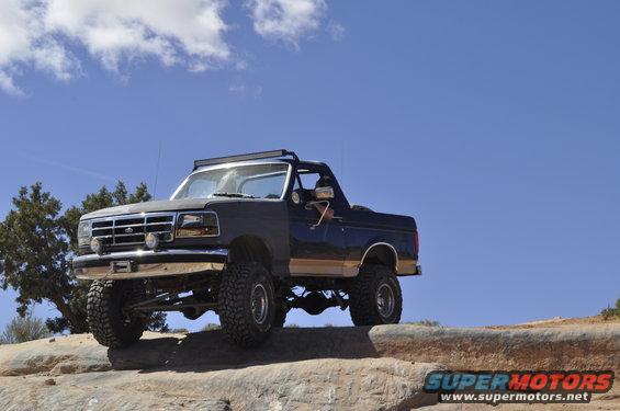 1991 Ford Bronco with lifted suspension and off-road tires parked on rocks under a blue sky