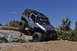 1991 Ford Bronco - A silver Jeep Wrangler navigates a rocky off-road trail under a clear blue sky.