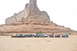 1991 Ford Bronco - A convoy of off-road vehicles is parked in a desert landscape, with a towering rock formation dominating the background.