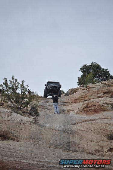 Jeep Wrangler on rocky terrain with person underneath