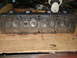 1964 Ford Galaxie - A close-up view of an engine cylinder head, showing its internal components and resting on a wooden surface.