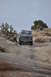 1991 Ford Bronco - 1991 Ford Bronco navigates a challenging rocky incline in a desert landscape.