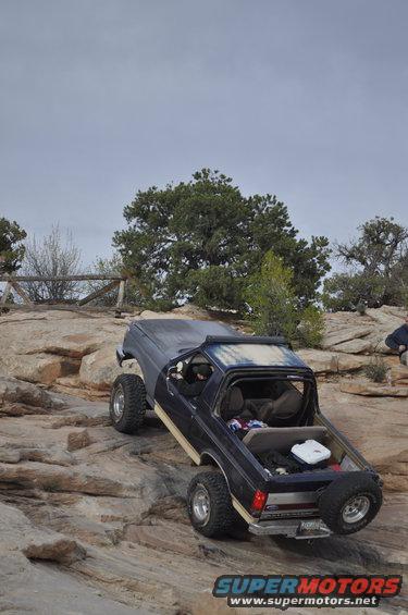 1991 Ford Bronco climbing rocky terrain, rear-mounted spare tire visible