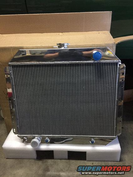 Shiny aluminum radiator with blue and white caps, sitting on foam in a box