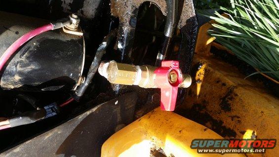 Red valve with brass fitting on yellow machinery