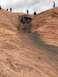 1991 Ford Bronco - An off-road vehicle is stuck in a precarious position on a steep, rocky incline while onlookers observe.