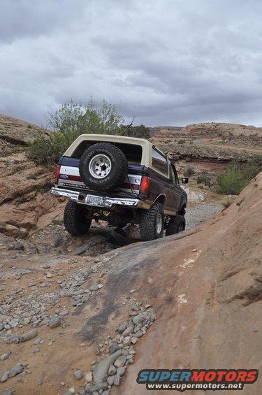 Ford Bronco climbing rocky trail, spare tire on back