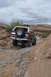 1991 Ford Bronco - A 1991 Ford Bronco navigates a challenging off-road path under a cloudy sky.