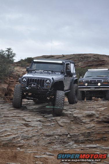 Silver Jeep Wrangler and black 1992 Ford Bronco on rocky trail
