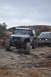 1991 Ford Bronco - Two modified SUVs, a Jeep Wrangler and a Ford Bronco, navigate a challenging rocky trail under an overcast sky.