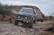 1991 Ford Bronco - Two off-road vehicles, a Ford Bronco and a Jeep Wrangler, navigate a rocky trail under an overcast sky.