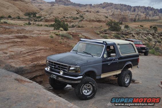 1991 Ford Bronco and red Jeep Wrangler on rocky terrain