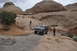 1991 Ford Bronco - A Ford Bronco navigates a challenging off-road course in a desert landscape under a cloudy sky.