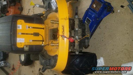Cub Cadet lawn tractor engine and transmission assembly with wiring. A blue container is to the right