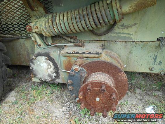 Rusty hub assembly and suspension part of a green vehicle, with a large coil spring