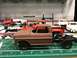 1989 Ford Bronco - A partially assembled model truck sits on a workbench, surrounded by other unfinished vehicle models.