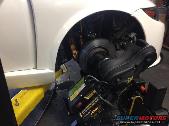 Wheel alignment machine attached to a white car's front wheel assembly