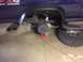 1982 Ford Bronco - The rear suspension and axle of a blue truck are visible, with the wheel removed and the vehicle supported by a jack stand.