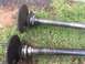 1982 Ford Bronco - Close-up of two vehicle axle shafts with their associated hubs and bearings resting on a grassy surface.