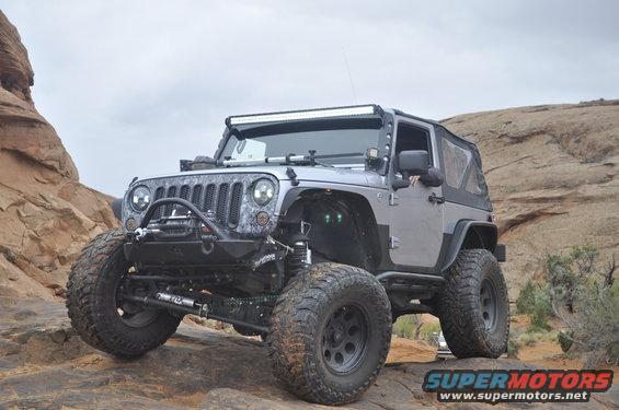Modified Jeep Wrangler JK on rocky terrain, front end visible with aftermarket bumper and light bar