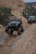 1991 Ford Bronco - Two modified off-road vehicles navigate a challenging rocky terrain in a desert landscape.