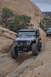 1991 Ford Bronco - A modified Jeep Wrangler tackles a challenging off-road trail in a rocky, desert landscape, with another vehicle following.