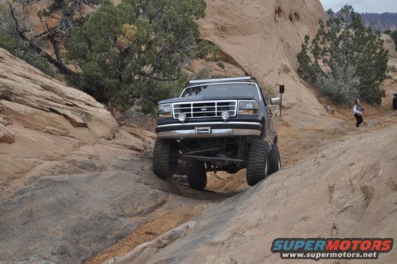Black Ford Bronco on rocky terrain, front view with lifted suspension and off-road tires