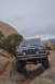 1991 Ford Bronco - A dark blue Ford Bronco navigates a rocky off-road trail under an overcast sky.