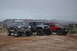 1991 Ford Bronco - Three modified off-road vehicles are parked in a desert landscape under a cloudy sky.