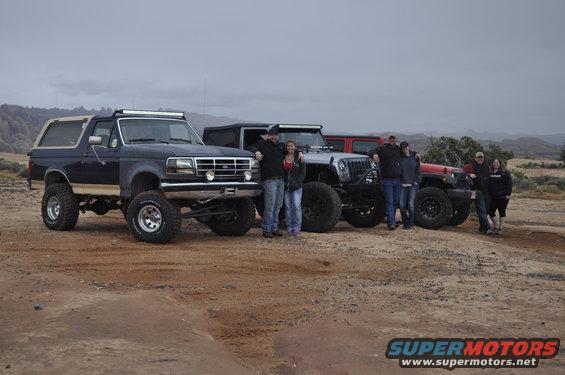 Dark blue 1991 Ford Bronco with lifted suspension and light bar parked with other off-road vehicles