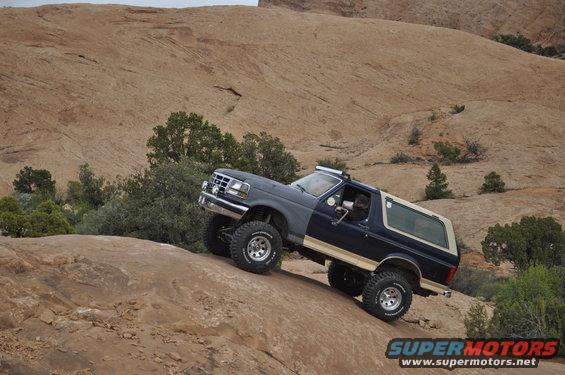 1991 Ford Bronco climbing a steep, rocky hill with sparse vegetation and a sandstone landscape