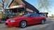 1976 Pontiac Trans Am - A red coupe is parked outside a rustic antique store, with a vintage gas pump and truck visible.