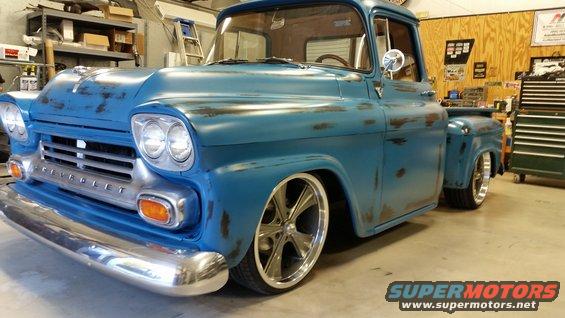 Blue 1958 Chevrolet Apache pickup truck with chrome bumper and custom wheels, parked indoors