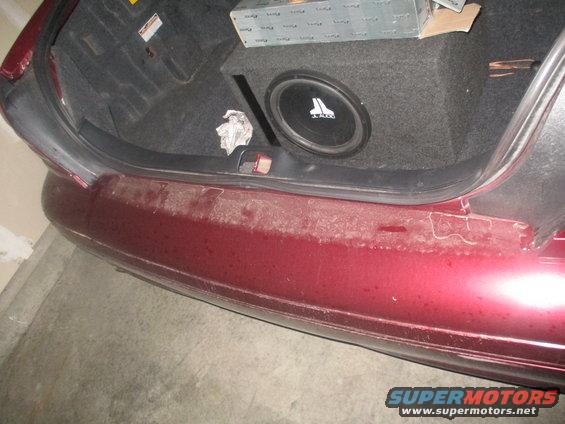 Car trunk with a JL Audio subwoofer box and some boxes stacked on top. The bumper is dirty