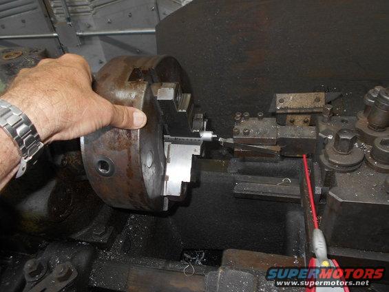 Hand holding a lathe chuck with a part being machined inside